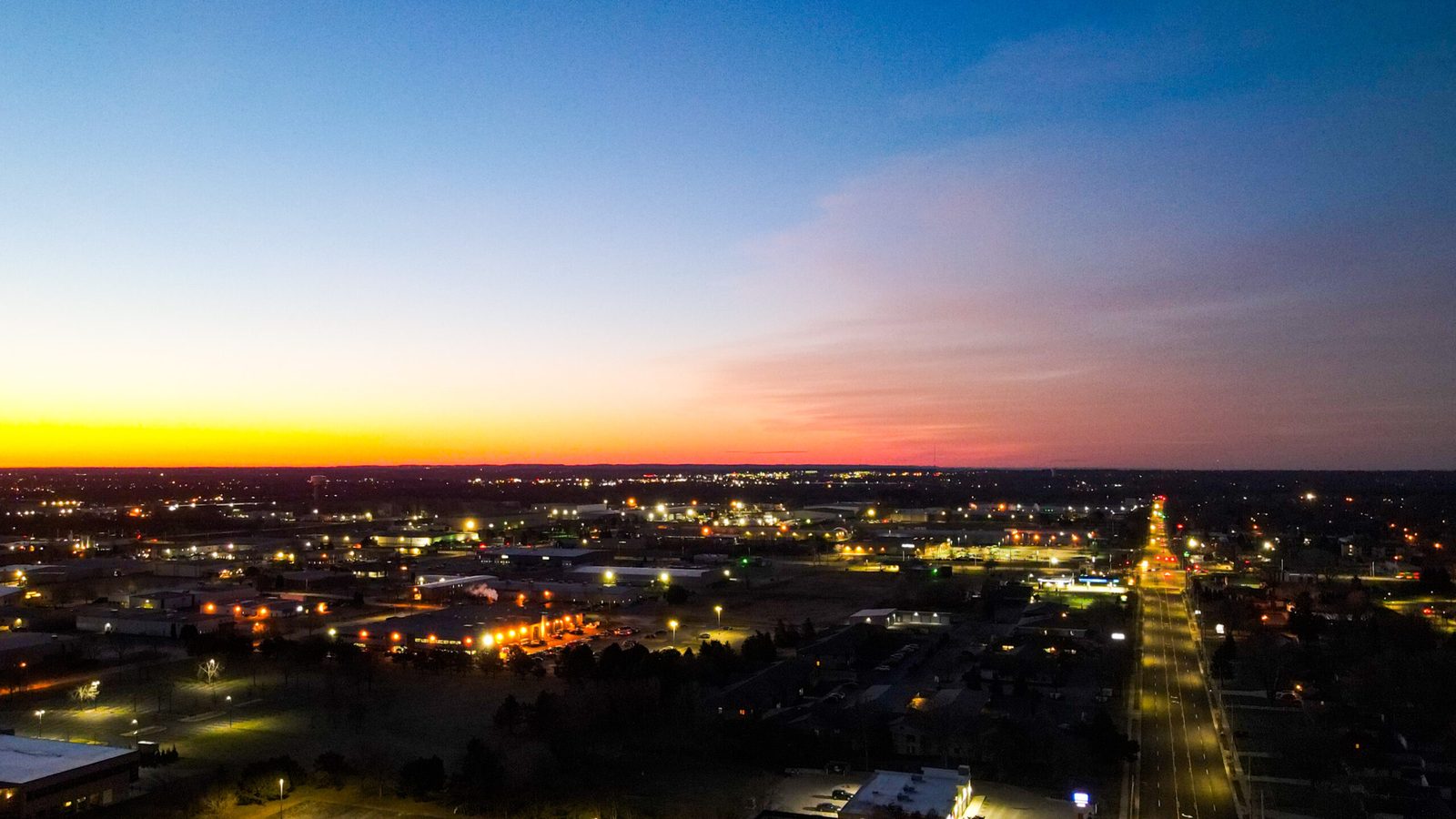 Aerial view of the Fox Cities at dusk, with streetlights and a sunset sky.
